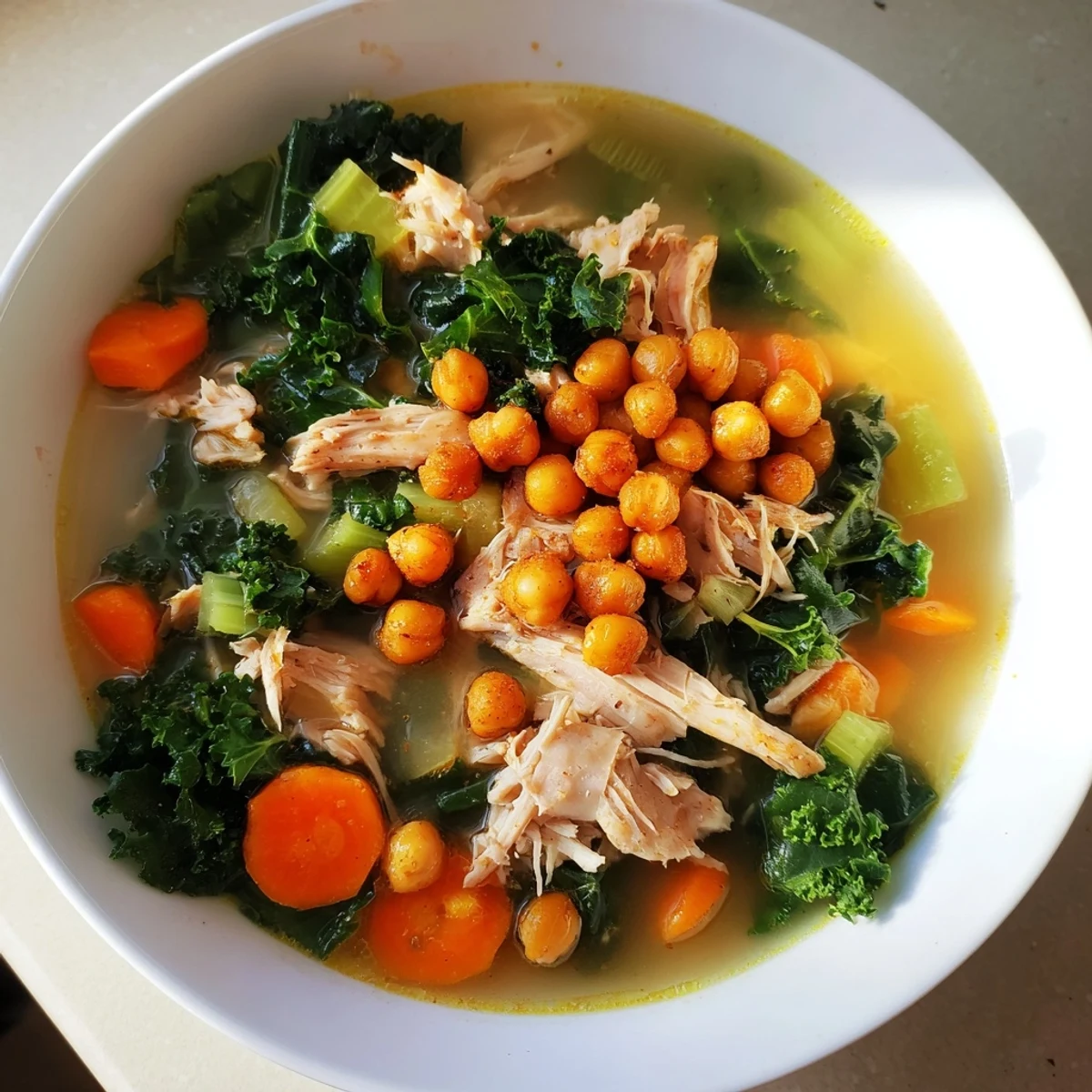 Steaming bowl of Chicken Kale Soup with crispy chickpeas, a healthy and filling meal.