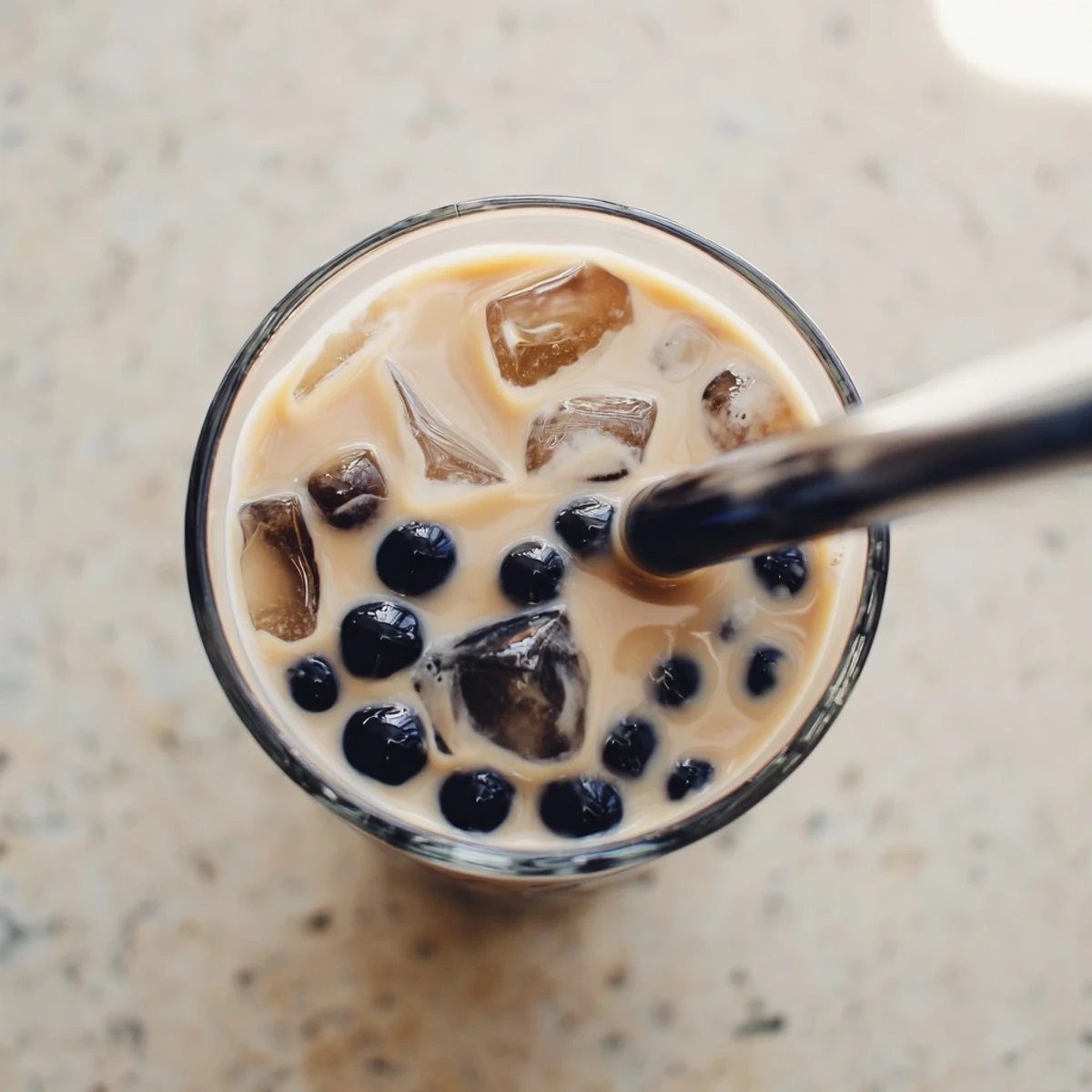 A single glass of Boba Tea Hack showcases sweetened condensed milk swirls and soft, chewy pearls in creamy tea.