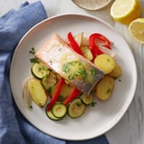 Golden salmon fillets rest atop roasted colorful vegetables, bathed in rich lemon butter sauce.