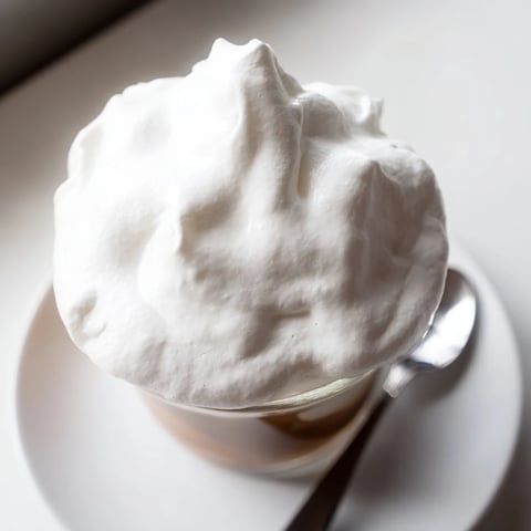 Fluffy Starbucks cold foam, swirled atop iced coffee, promises a refreshing, barista-style beverage treat.