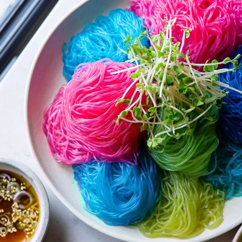 Vibrant bowl of chilled Neon Noodle Clouds, swirled with colorful strands and savory dipping sauce.