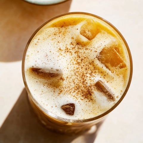 Iced Chai Tea with Cold Foam served in a clear glass, layered over ice cubes and topped with velvety foam dusted with cinnamon.