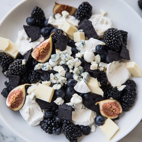 A vibrant Deep Indigo Midnight Sky cheese board featuring creamy goat cheese and glistening fruit.