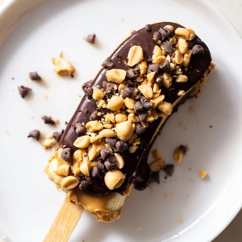 Homemade Frozen Banana Chocolate Pops offering a refreshing bite with creamy peanut butter and sweet banana flavors.