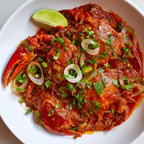 Close-up of vibrant Singaporean Chili Crab, the rich tomato sauce hugging succulent crab pieces.