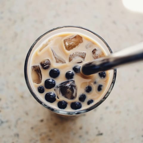 A single glass of Boba Tea Hack showcases sweetened condensed milk swirls and soft, chewy pearls in creamy tea.