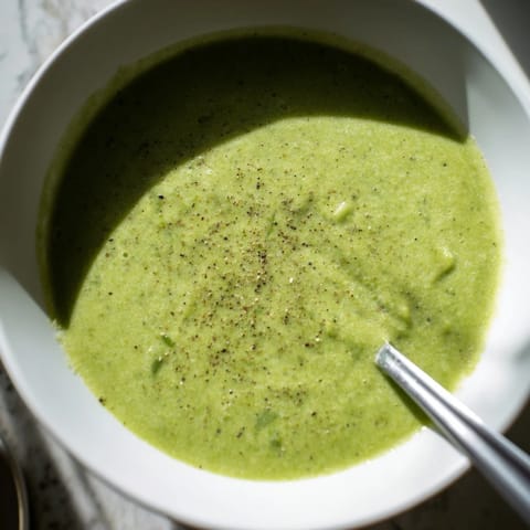 The creamy texture of this Big Green Immunity-Boosting Vegetable Soup shines in a rustic mug with broccoli florets on top.