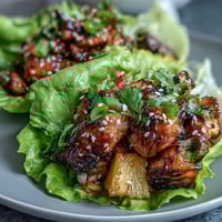 Fresh teriyaki chicken and juicy pineapple wrapped in crisp lettuce leaves with colorful vegetables and herbs.  